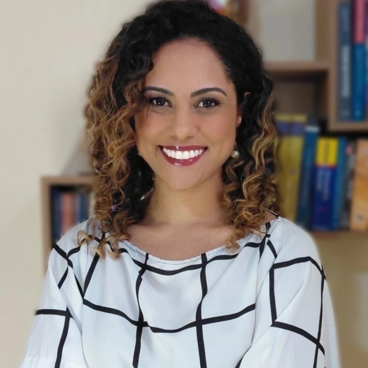 Denise Neri, mentora e advogada, sorrindo em frente a uma estante de livros